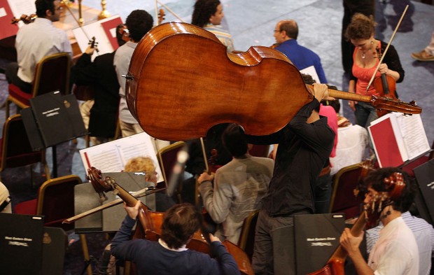 LONDON, ENGLAND - AUGUST 21: A double bass player in The West-Eastern Divan youth orchestra manoeuvres his instrument into position for a rehearsal in the Royal Albert Hall ahead of their performance in the BBC Proms tonight on August 21, 2009 in London, England. The orchestra was founded by Daniel Barenboim, an Argentine of Jewish descent and the late Palestinian-born Edward Said in 1999 and is based in Sevilla, Spain. The project involves young musicians from a variety of countries in the Middle East including Egypt, Iran, Israel, Jordan, Lebanon, Palestine and Syria. Although not described as a political project the orchestra serves as an example of Barenboim and Said's vision of understanding and collaboration between Israelis and Palestinians.