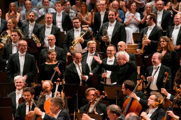 British conductor Sir Simon Rattle stands amidst of members of the Berlin Philharmonic Orchestra (Berliner Philharmoniker) after conducting his last symphony concert as the orchestra's chief conductor on June 20, 2018 in Berlin. 