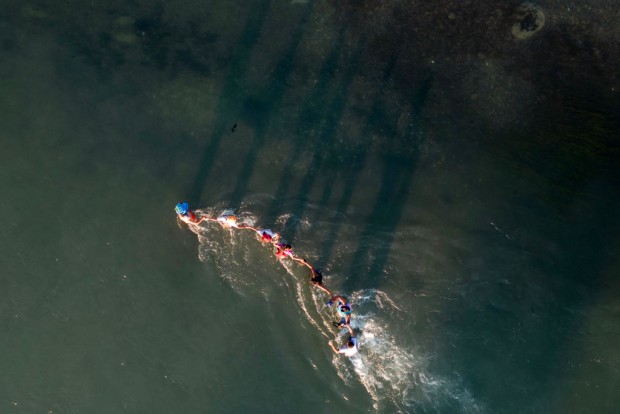 TOPSHOT - This aerial picture taken on September 23, 2023 shows a family holding on as they try to navigate swift currents in the Rio Grand river as they cross the US-Mexico border to Eagle Pass, Texas. The struggles of immigrant families are the focus of the children's book, 'Pancho Rabbit and the Coyote,' and its chamber opera adaptation by Anthony Davis.
