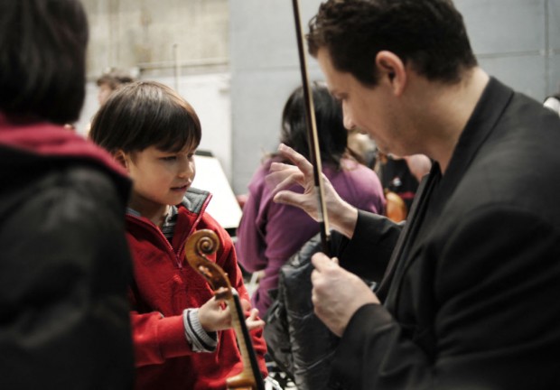 A child is introduced to the violin by a musician at the Lyon Opera on the second day of 